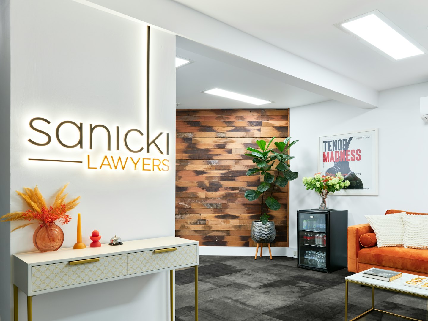 Área de recepción de oficina moderna con sofá y letrero de Sanicki Lawyers.