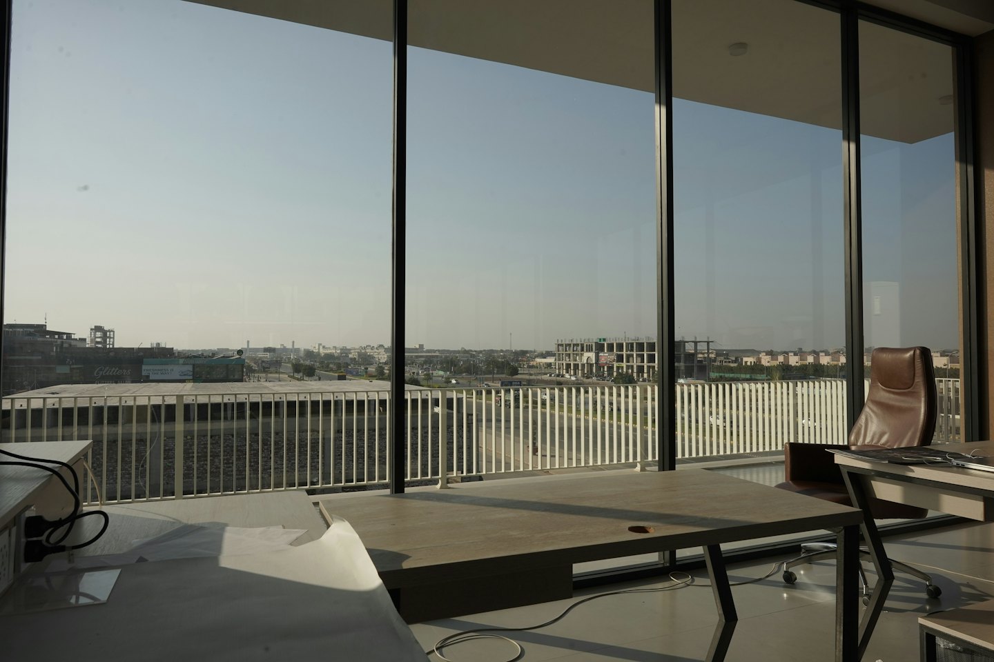 Oficina moderna con escritorio y silla junto a grandes ventanales con vistas a la ciudad.